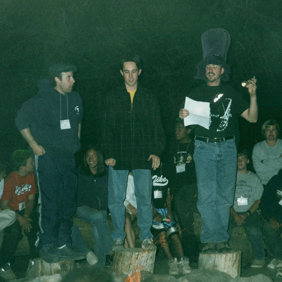 Vintage photo of Silver Lake Band Camp participants standing on logs and performing a skit during a nighttime campfire gathering.