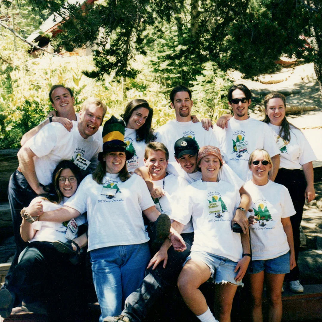 Vintage group photo of Silver Lake Band Camp staff and campers wearing matching camp shirts outdoors among trees.