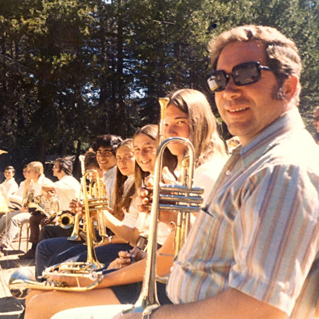 Vintage photo of Silver Lake Band Camp musicians seated outdoors holding brass instruments during a group rehearsal.