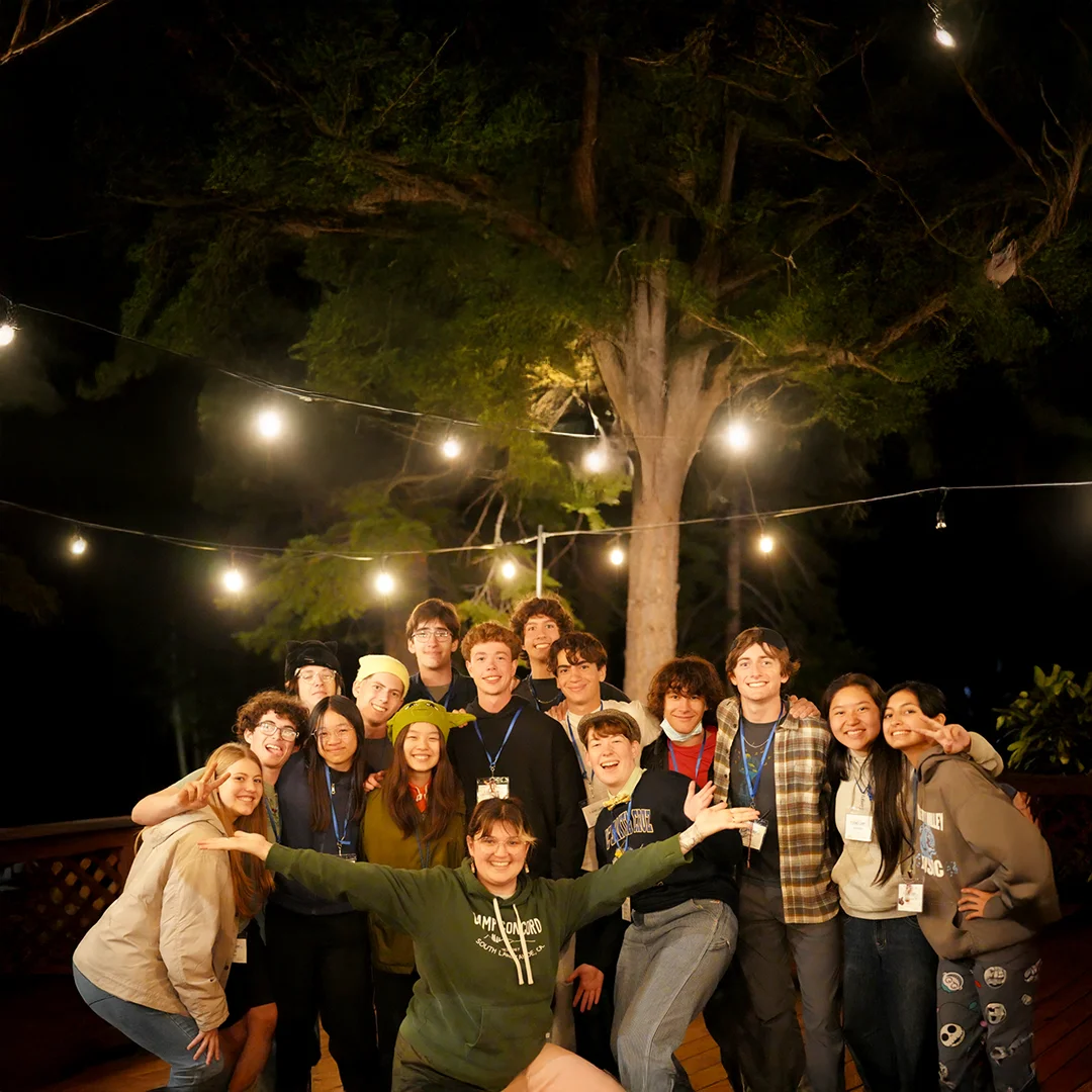 Silver Lake Band Camp Evening Community Gathering Campers and staff smiling together at an evening gathering under string lights at Silver Lake Band Camp.